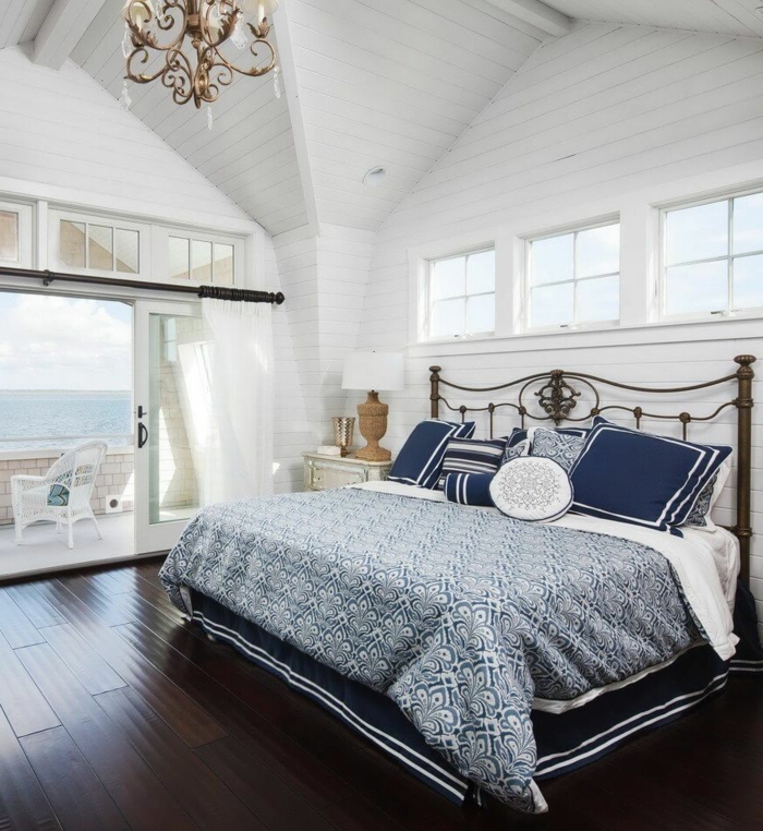 Schlafzimmer mit Meeresblick, blaue Bettwäsche, Decke mit Dachschräge, Maritime Möbel, Boden aus Holz, 
