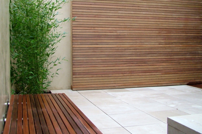 ein Holz Sichtschutz, eine Bank und grüne Pflanze, Fliesen Bodenbeläge - minimalistischer Garten