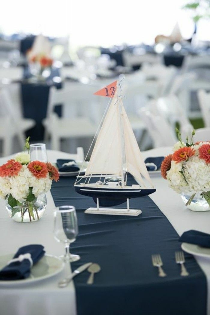 Maritime Tischdeko, orange und weiße Blumen, kleines Segelboot in blau und weiß, blauer Tischläufer, weiße Tischdecke