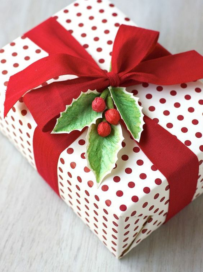 Geschenkverpackung basteln aus schwarzem Band, Geschenkpapier auf rote Punkte und ein grünes Zweig aus Papier