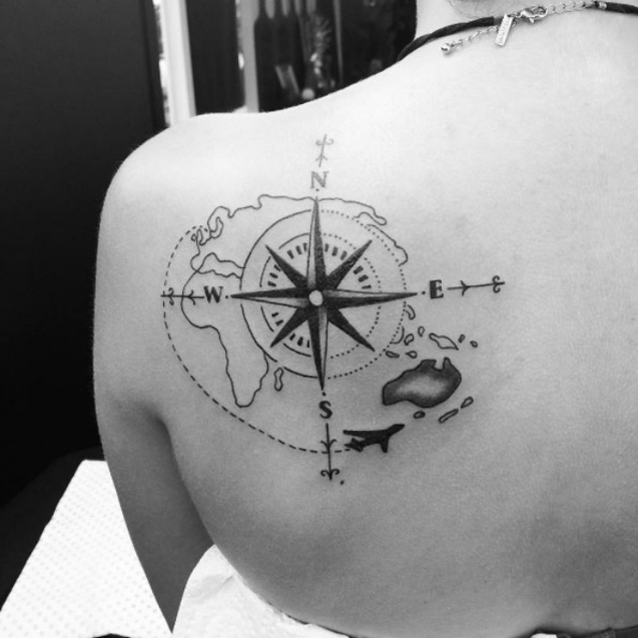 das ist eine ganz tolle idee für einen compass tattoo auf dem schulter - eine schwarze tätowierung mit einem kompass und einer weltkarte auf dem schuoterblatt und ein flugzeug