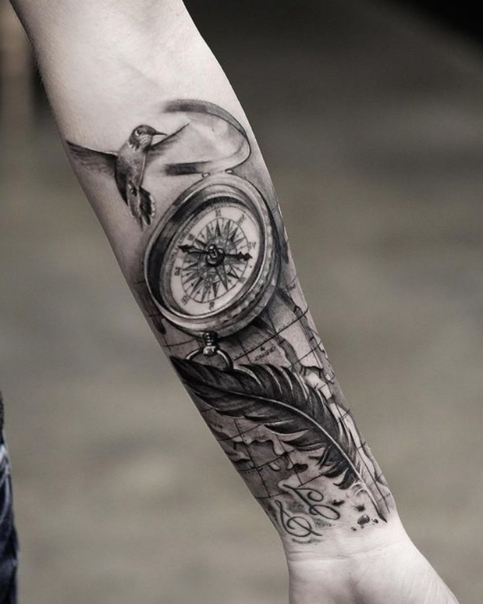 ein vogel, ein schwarzer kompass und eine lange schwarze feder - idee für einen compass tattoo auf der hand