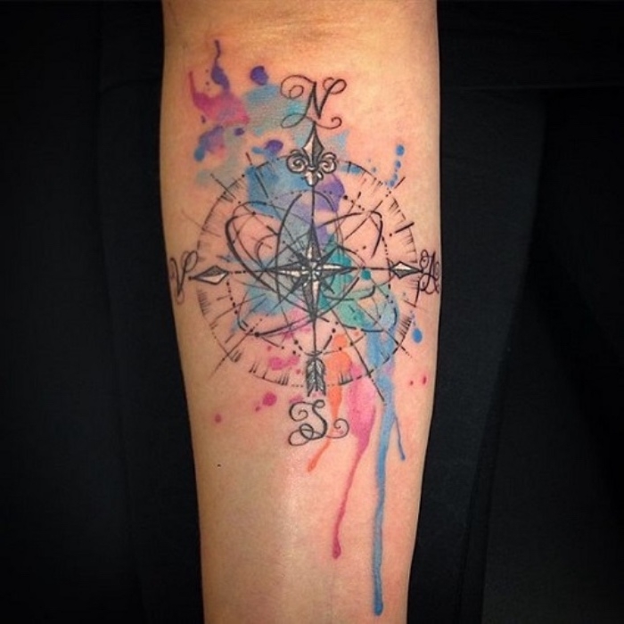 idee für einen bunten tollen tattoo mit einem großen schwarzen kompass mit schwarzen pfeilen - ein tattoo auf der hand