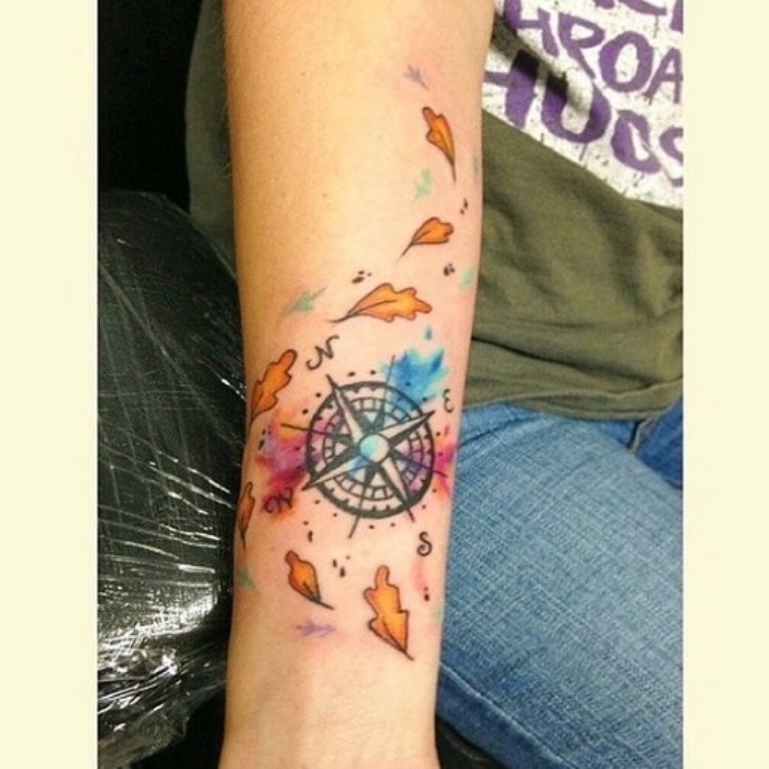 das ist eine idee für eine schöne bunte tätowierung mit orangen blättern und einem schwarzen kompass - eine hand mit compass tattoo