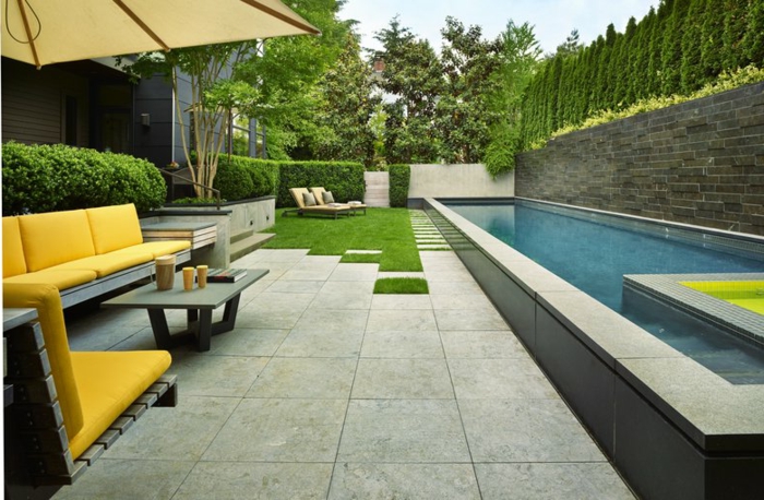 grüner Rasen Liegestühle gelbe Gartenmöbel ein Schwimmbad puristischer Garten