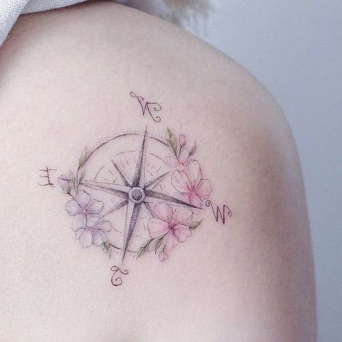 eine sehr schöne tätowierung mit kleinen pinken und lila blumen und einem kompass auf dem