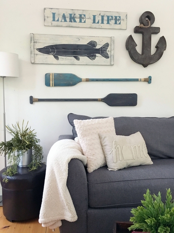 Maritime Möbel. großes blaues Couch, nautische Dekoration an die Wand, zwei aufgehängte Ruder und ein Anker, grüne Pflanzen