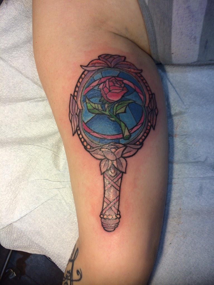 ein spiegel und eine rote rose mit grünen blättern - idee für einen ausgefallenen rosen tattoo - die schöne und das biest 