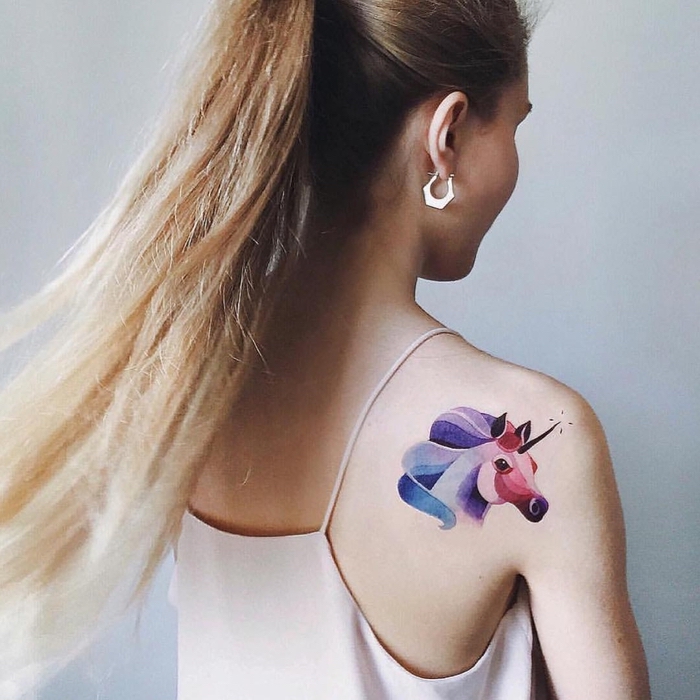 ein Einhorn Tattoo an dem Schulter in lila, roter und blauer Farbe Watercolor Tattoo