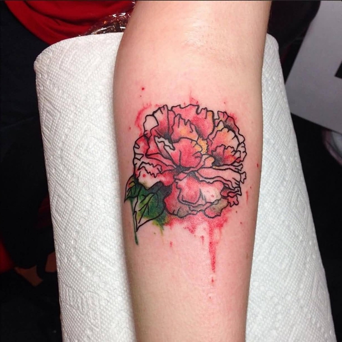 Watercolor Tattoo eine rote Blume und ihre grüne Blätter an dem Arm ganz kunstvoll