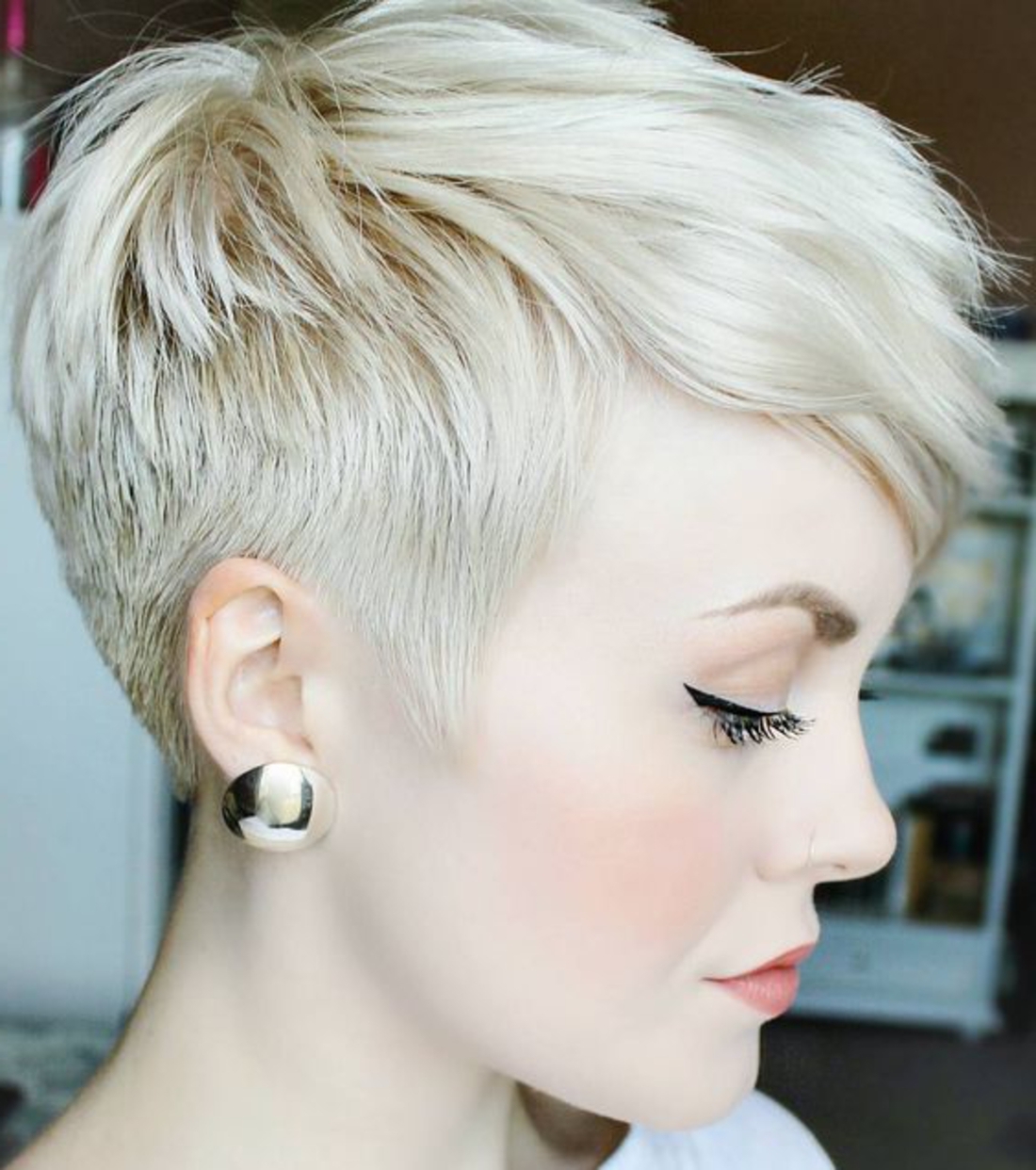 Kurzhaar Undercut blonde Haare massive silberne Ohrringe, weiße Bluse, schöne Schminke