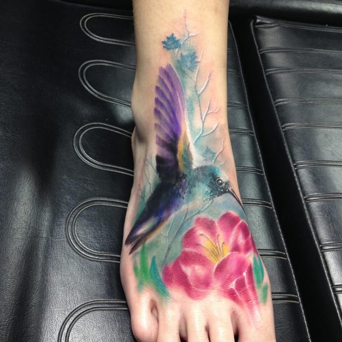 ein Kolibri in bunten Farben auf einer rosa Blumen - andere Zweige - Wasserfarben Tattoo
