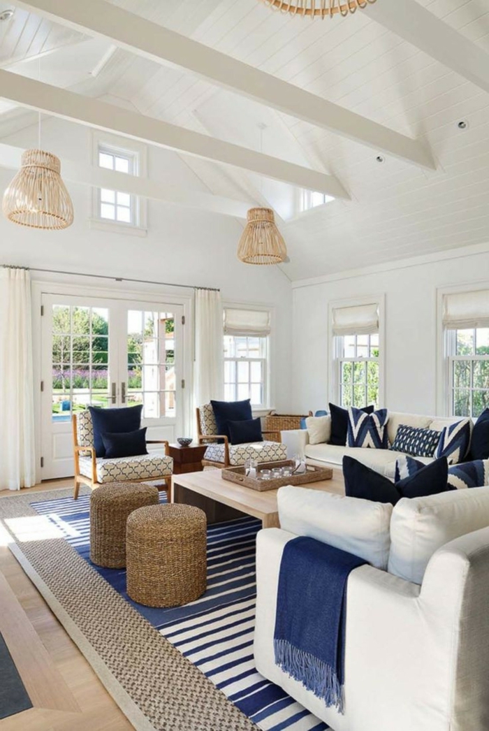 geräumiges Wohnzimmer mit großen weißen Sesseln, maritime Farben, dunkelblaue Kissen und Decken, Teppich in blau und weiß, 
