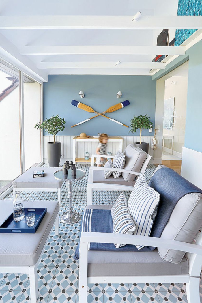 Wohnzimmer maritimer Stil, zwei große graue Sessel mit blauer Decke, zwei aufgehängte Ruder an blaue Wand, 