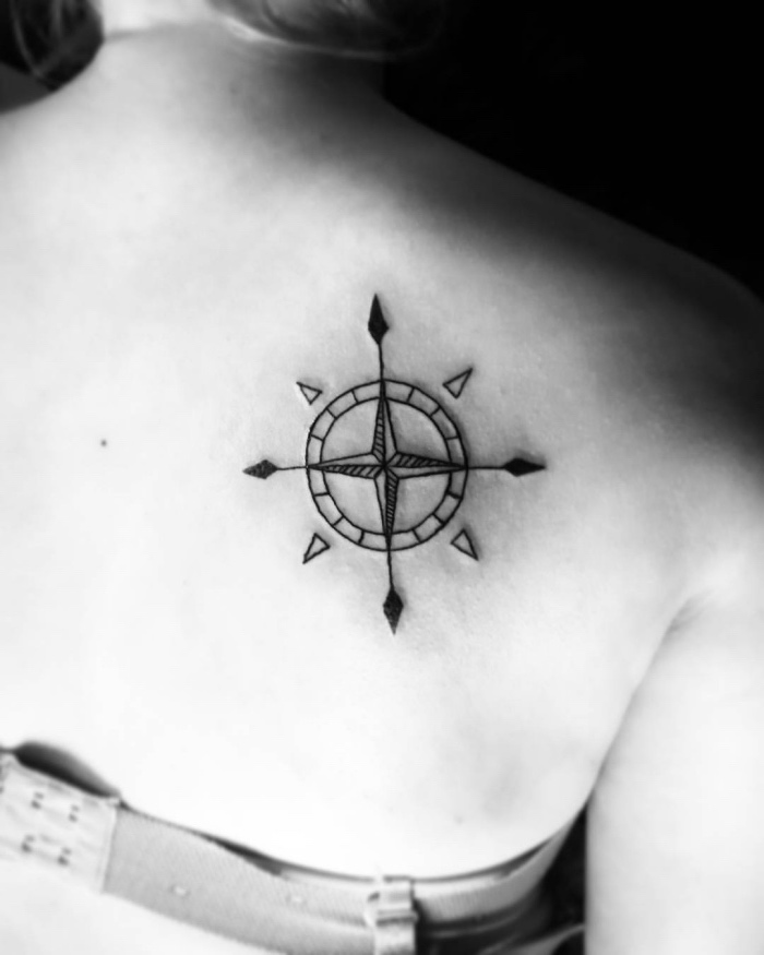 idee für einen schwarzen compass tattoo auf dem schulterblatt - hier ist ein schwarzer kleiner kompass mit kleinen schwarzen pfeilen auf dem schukterblatt einer jungen frau