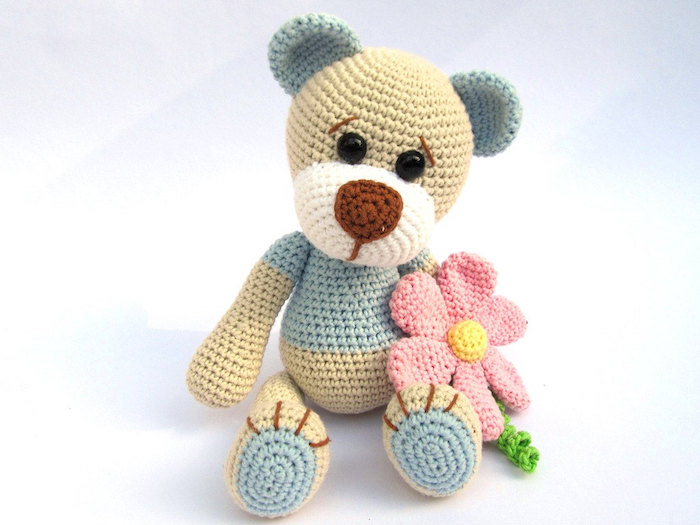 ein entzückender Teddy in einigen Farben, der Bär hat rosa Blume in der Hand - Amigurumi für Anfänger 