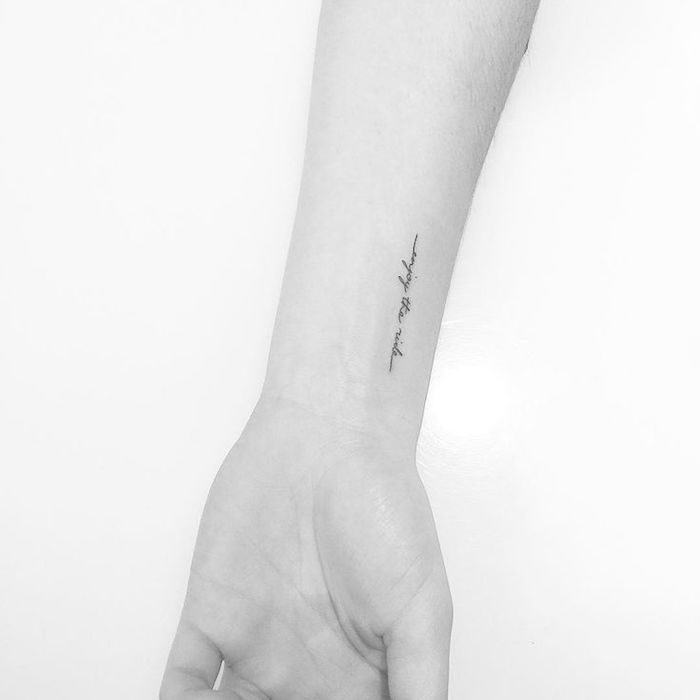 eine hand einer frau mit einem kleinen schwarzen tattoo auf ihrem handgelenk 