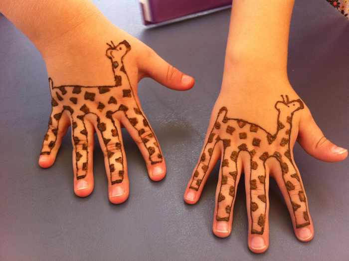 zwei kleine Schwestern mit Henna Tätowierungen von Giraffen an den kleinen Händen 