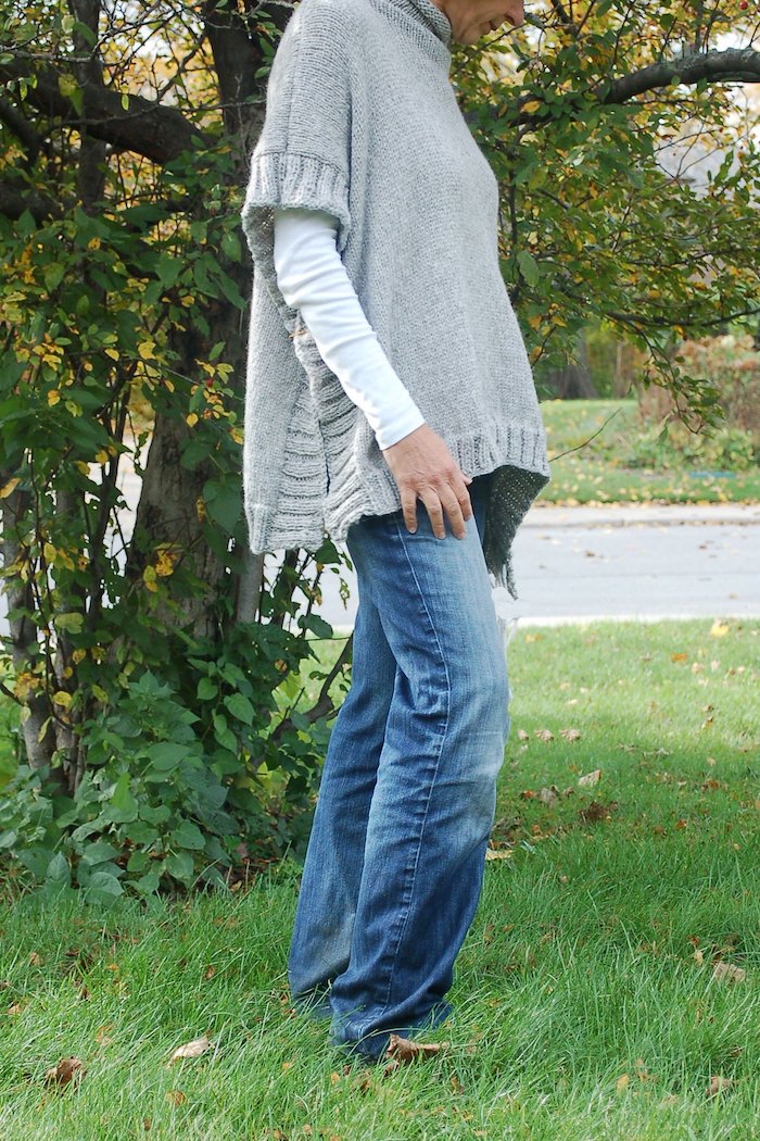 einen grauen Poncho stricken mit Muster an Rändern mit Jeans kombiniert