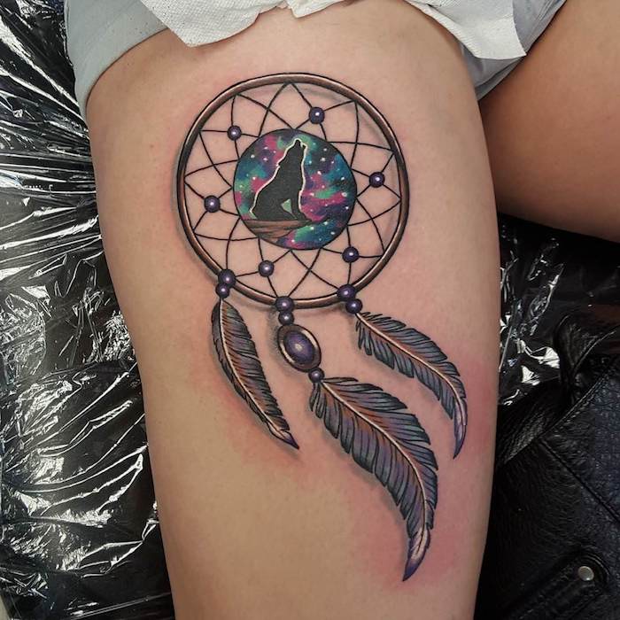 tattoo mit einem schönen schwarzen kleinen heulenden wolf und einem großen traumfänger und drei schwarzen federn