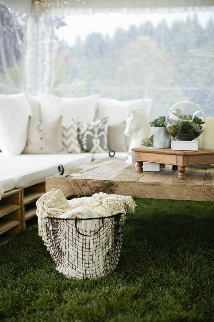 ein tisch und sofa aus alten paletten mit kleinen weißen kissen und ein terarrium - idee zum thema palettenmöbel selber bauen 