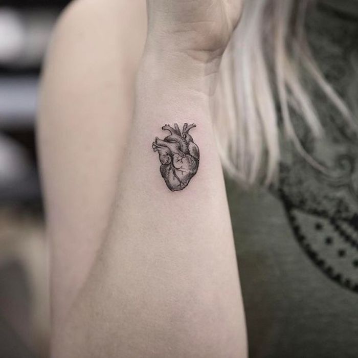 blonde Frau mir einem Mini Tattoo in der Form des menschlichen Herzen