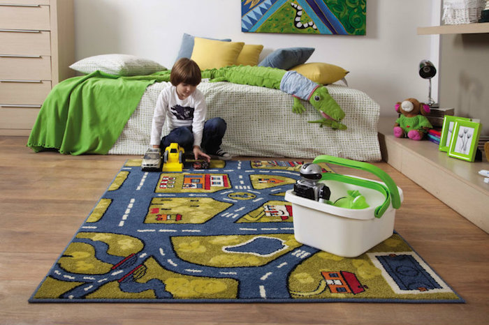 ein Junge spielt im Kinderzimmer, Polizeiauto, Bagger, Holzkommode, gelbe Bettkissen