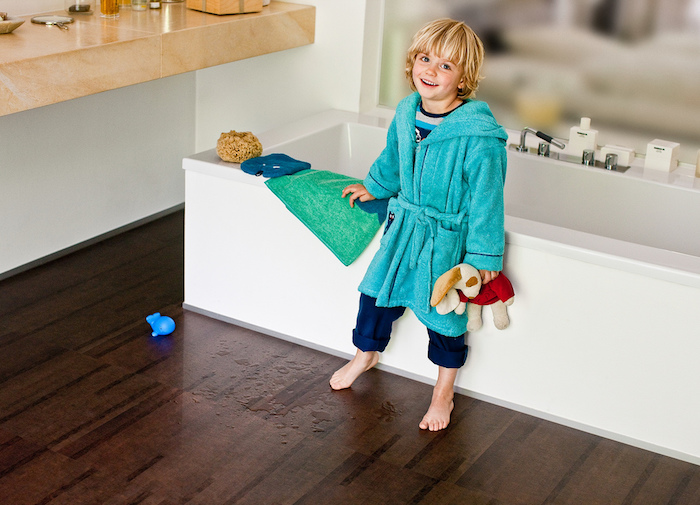 ein glückliches Kinde mit blauem Morgenmantel aus Plüsch, Marmortischplatte