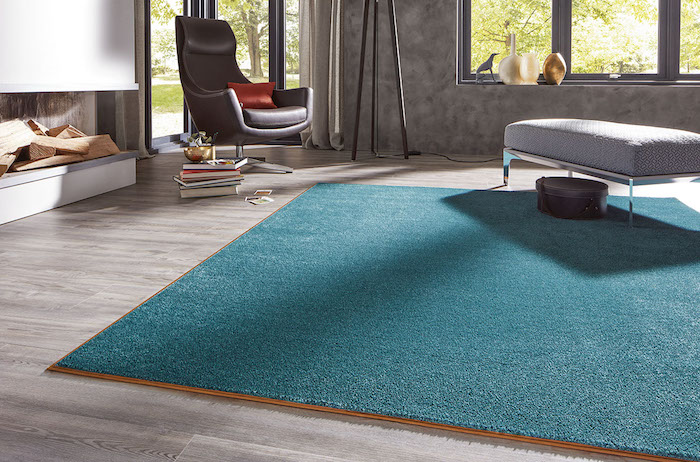 ein blauer Teppich ein brauner Sessel und Laminat Boden günstiger Bodenbelag