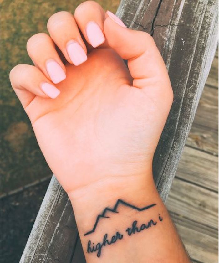 eine gebrochene Linie in der Form von Gebirge und Tattoo Schriftzüge am Handgelenk