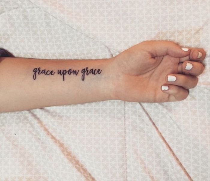 ein religiöses Zitat auf dem Handgelenk von einer Frau mit weißen Nagellack - Tattoo Sprichzüge