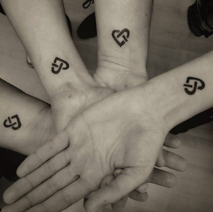 vier Geschwister mit einem minimalistischen Herzen Tattoo an dem Handgelenk - Geschwister Tattoo 