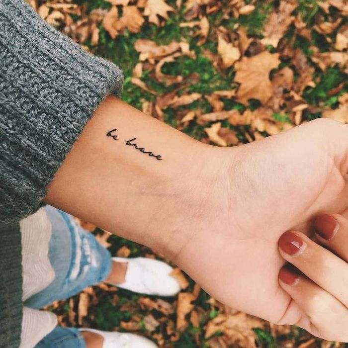 Kleines Tattoo am Handgelenk, Be Brave Tattoo in feiner Schreibschrift, roter Nagellack 