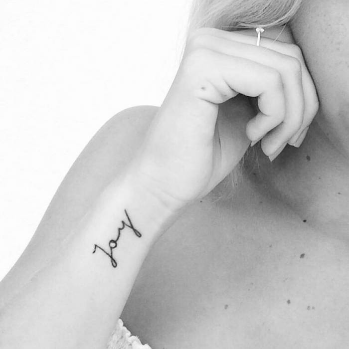 Kleines Joy Tattoo am Handgelenk, Tattoo in Schreibschrift am Unterarm, Tattoos für Frauen 