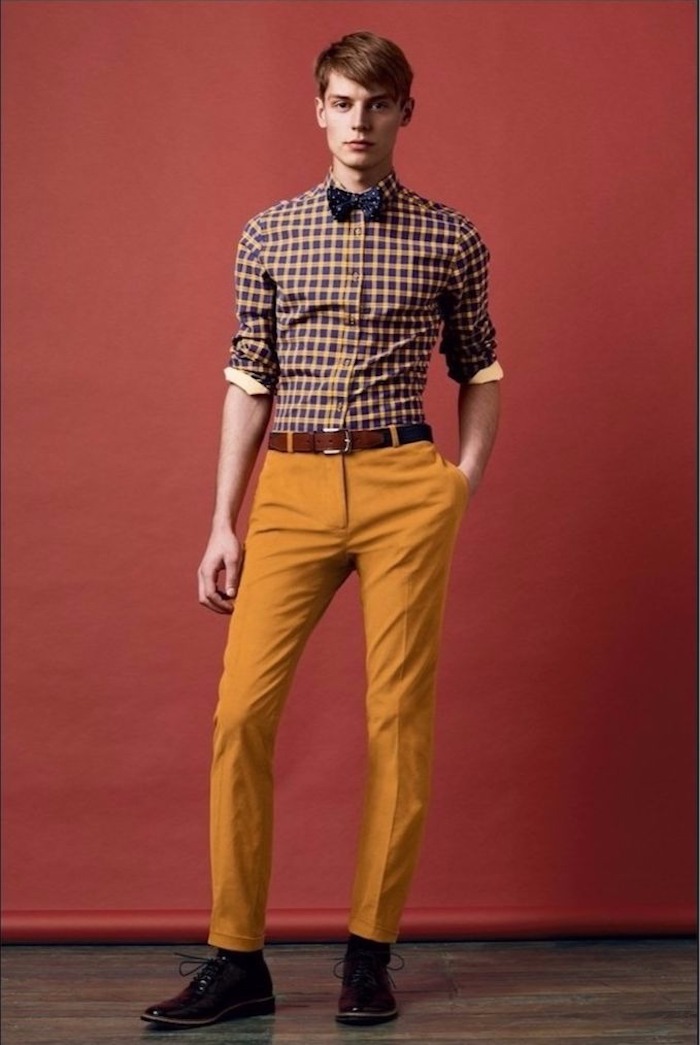 schlanker Mann mit gelb-oranger Hose, Karo-Hemd, dunkelblaue Fliege mit Print