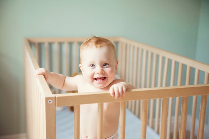 foto von einem frohen baby das im babybett baby im bett trittkanten matratze kinderzimmer