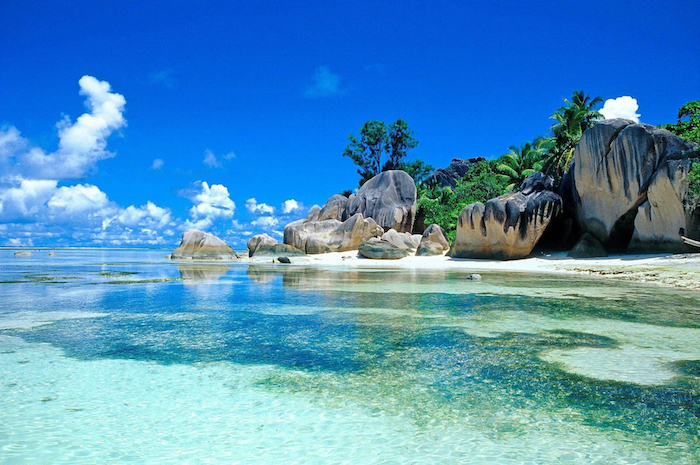 exotischer Ort neben dem Ozean, Strand mit Palmen und großen Felsen