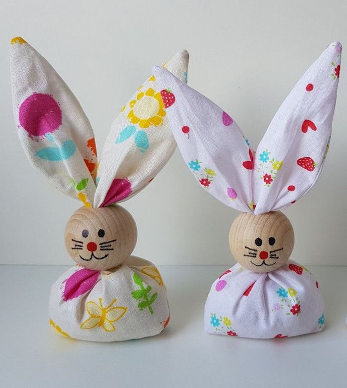 zwei kleine Hasen aus weißem Stoff mit Print, hölzerne Köpfe mit gemaltem Schnurrhaar