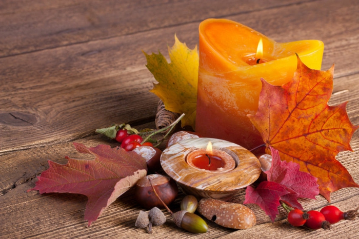 den Tisch herbstlich arrangieren, Kastanien, Eicheln, Herbstblätter und gelb-orange Kerze, herbstliche Nuancen