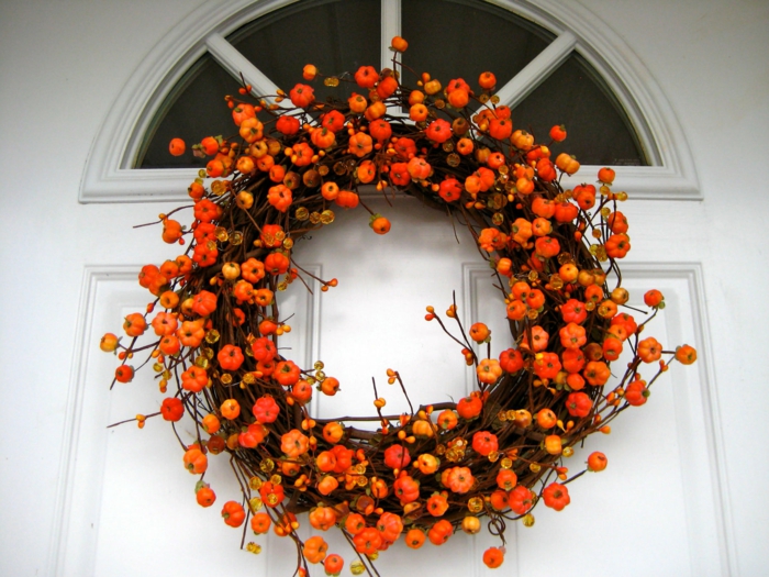 herbstlichen Kranz für die Eingangstür, kleine orange Kürbisse, die Farbe des Herbstes, Kontrast zur weißen Tür