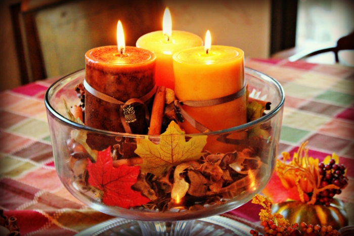 den Tisch herbstlich arrangieren, Kerzen in herbstlichen Nuancen und Herbstblätter in Glasschale