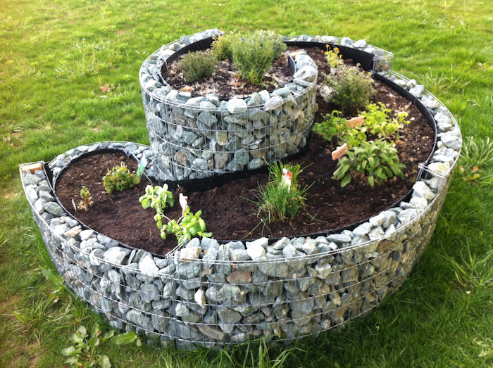 werfen sie einen blick auf diese idee zum thema kräuterspirale mit steinen und grünen pflanzen - idee zum thema gartengestaltung