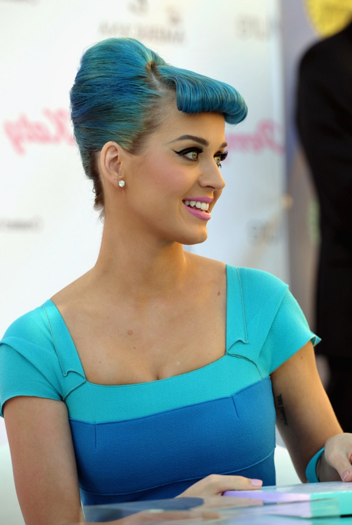 Katy Perry mit blauen Haaren, cooler Outfit, Kleid in Türkis, rosafarbene Lippen, Eyeliner und Mascara