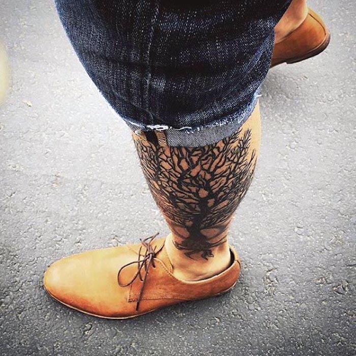 ein Tattoo am Bein wie Baum des Lebens ein Mann mit Jeans Shorts und orange Schuhe