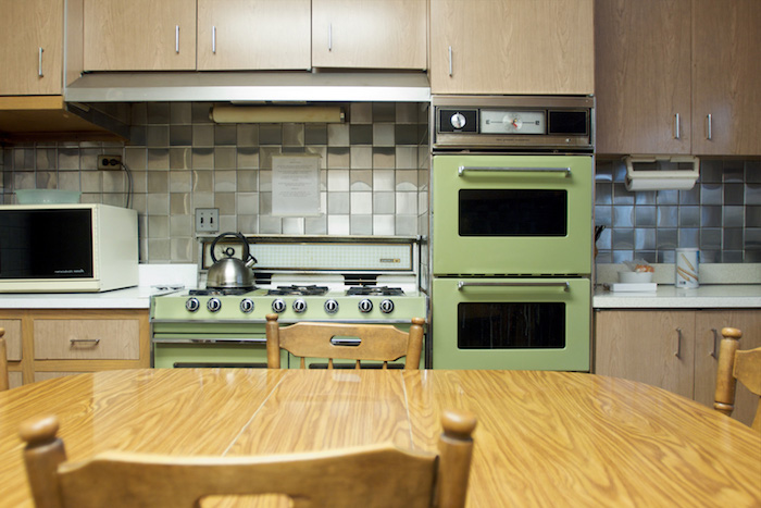 eine gemütliche Wohnküche mit einem alten Ofen in grüner Farbe und Möbel aus Holz