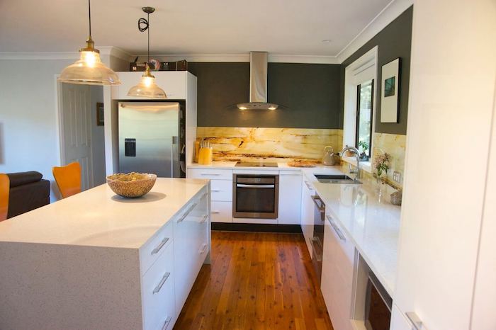 Wohnküche mit weißer Ausstattung, grau gestrichene Wände, Laminatboden und bunte Fliesen