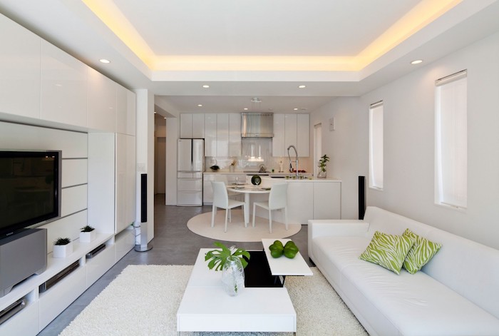 eine weiße Ausstattung von einer offenen Küche und Wohnzimmer, grüne Dekoration