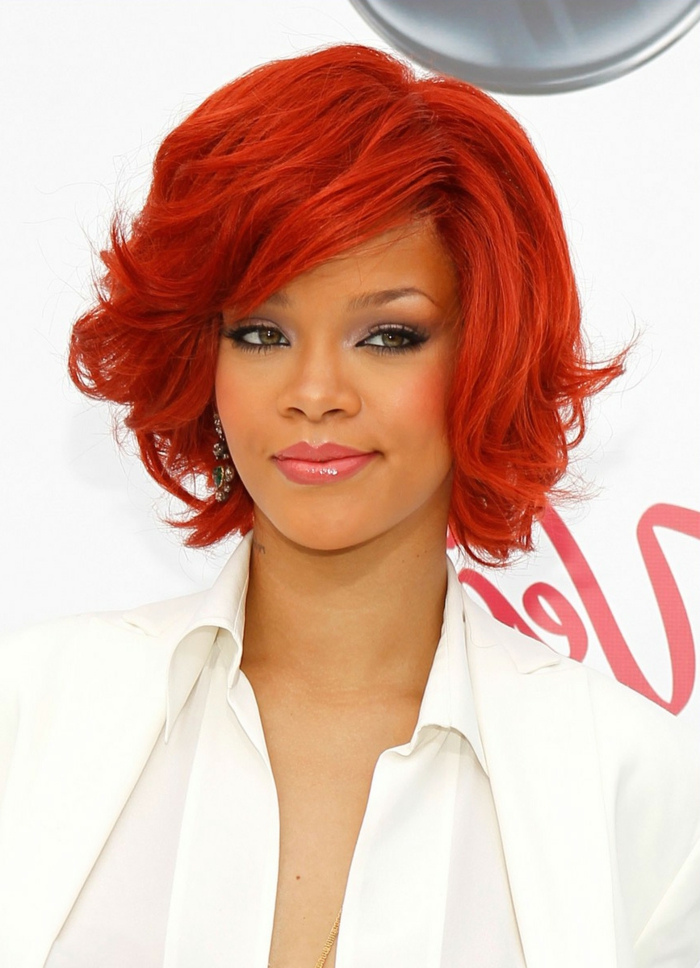 Rihanna mit roten Haaren, rote Haarfarbe und dunkler Teint, rosa Lippen, weißes Hemd