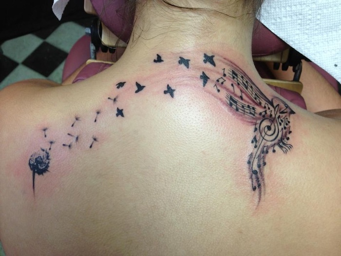 tattoo symbole, tätowierung mit blume, vögeln und noten am rücken