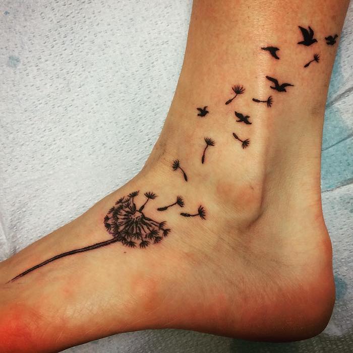 kleine tattoo motive, schwarze tätowierung mit pusteblumen-motiv am fuß